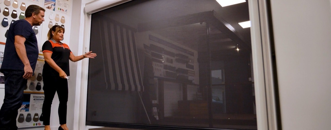 A Big Difference team member showing a customer an outdoor blind display and fabric samples in the Hendon showroom