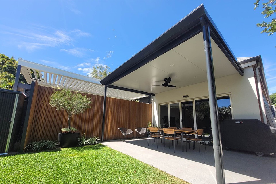 Charcoal-framed patio with an insulated ceiling and ceiling fan over paved outdoor dining