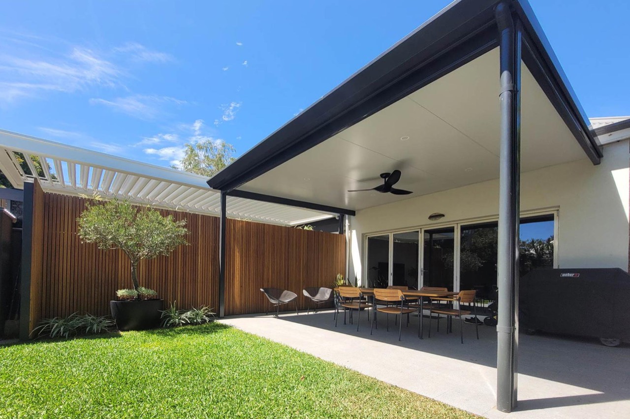 Charcoal-framed patio with an insulated ceiling over a paved dining area