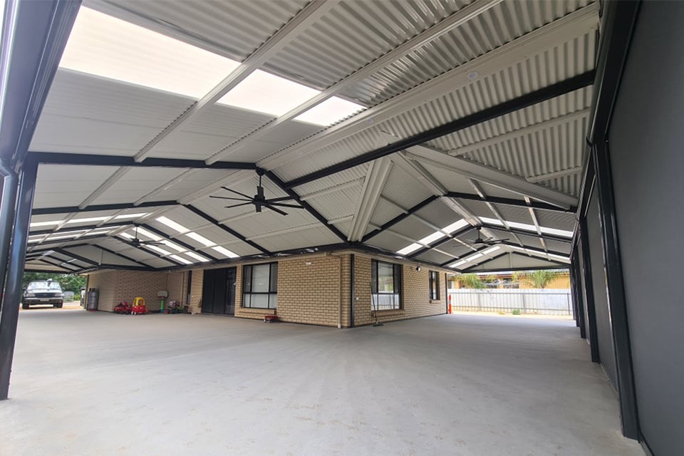 Large gable verandah with steel beams, polycarbonate roof lights and a ceiling fan over a concrete entertaining area