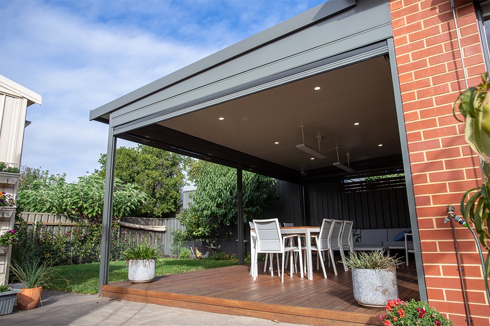 Skillion patio with an insulated ceiling and downlights over a timber deck beside a brick wall
