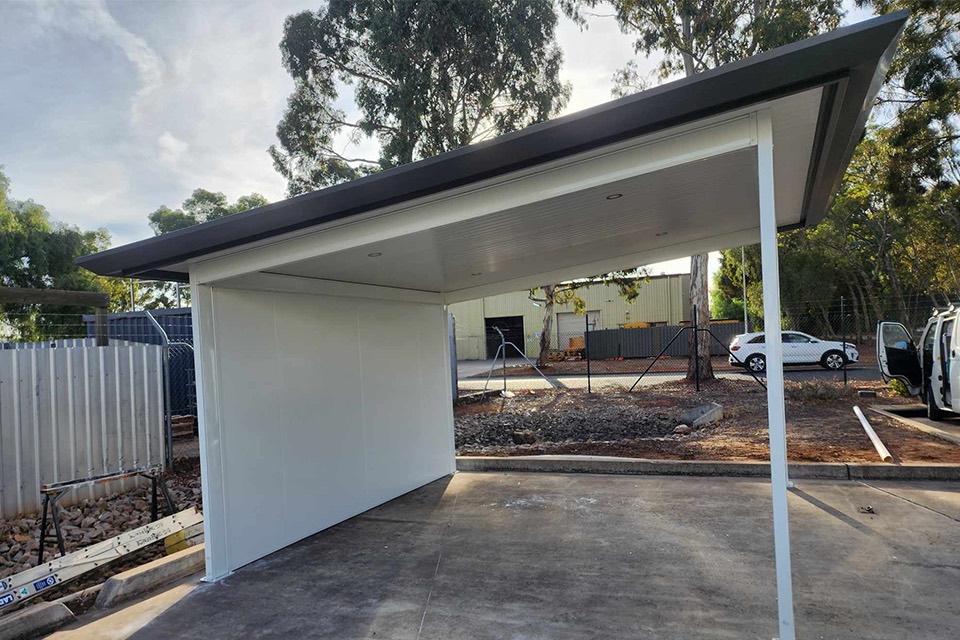 Skillion patio with a smooth white ceiling, charcoal fascia and a white infill wall over concrete