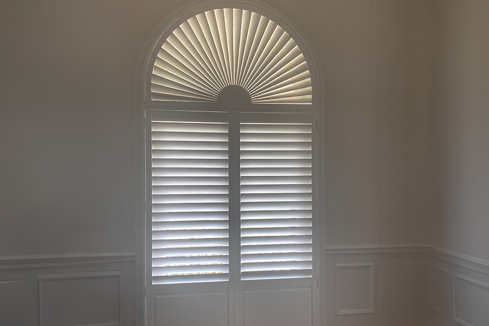 White plantation shutters with a sunburst arched top on an arched window