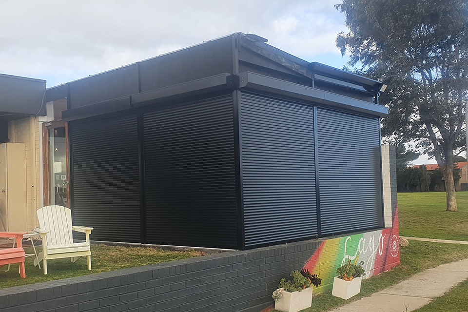 Charcoal roller shutters closing in a verandah along the front of a building