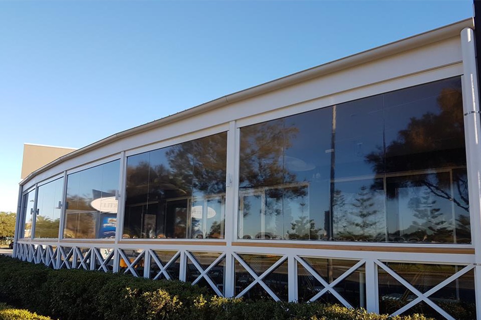 Long run of clear PVC blinds enclosing the curved verandah of a hospitality venue