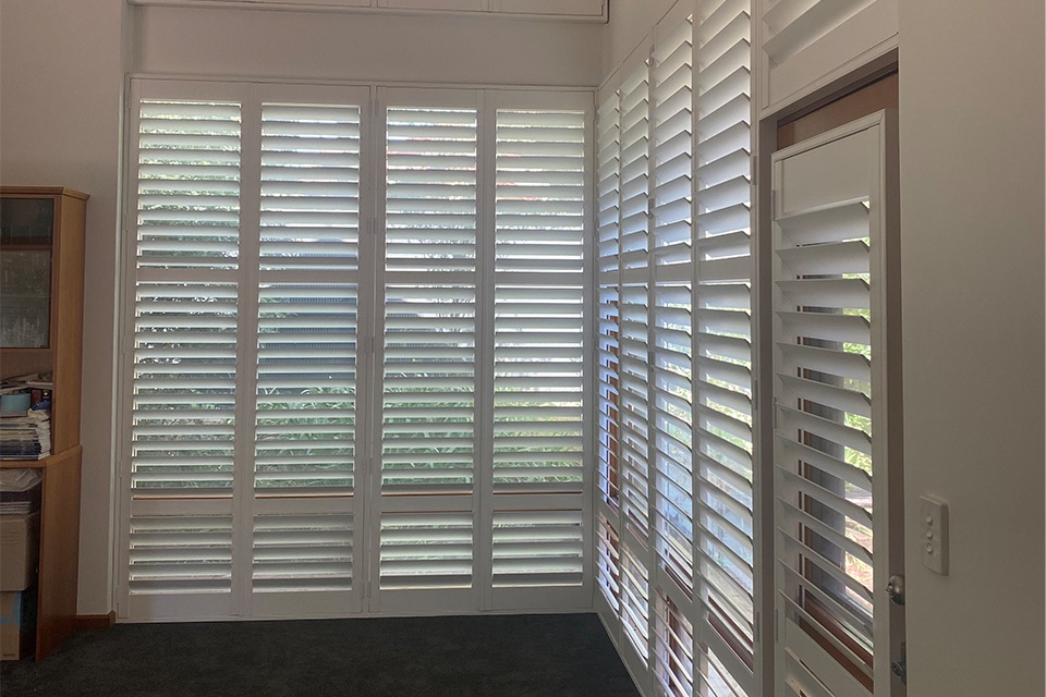 White plantation shutters fitted around a corner window