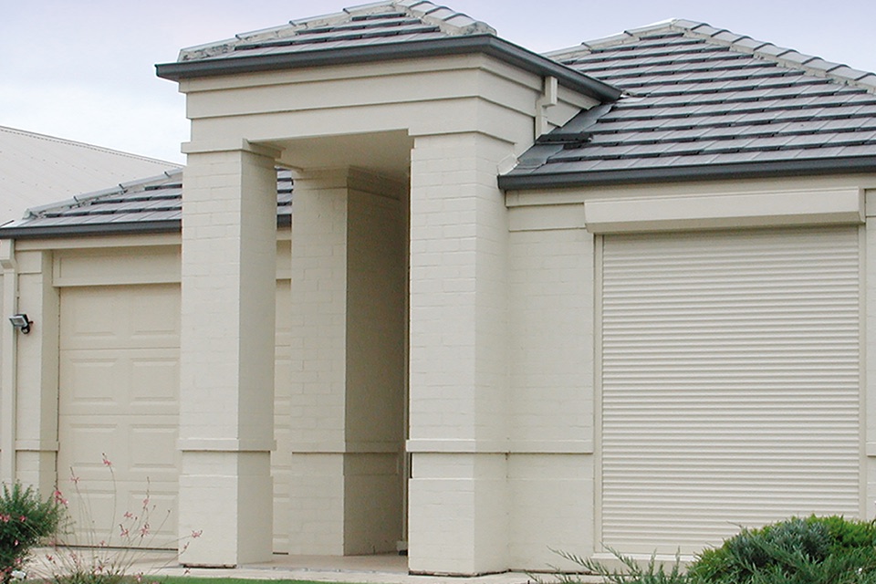 Cream roller shutter on the front window of a rendered home