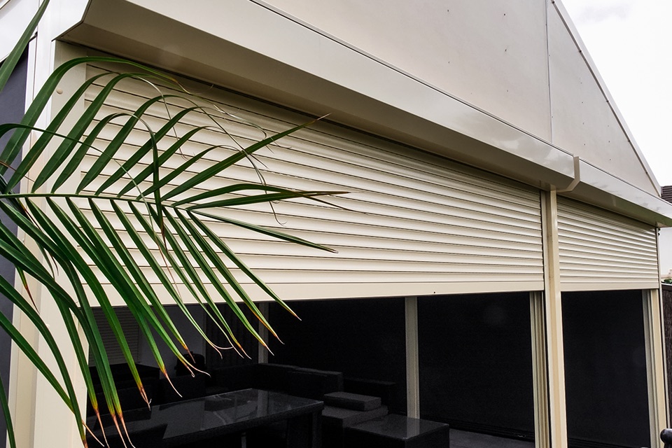 Cream roller shutters partly lowered around an outdoor entertaining area
