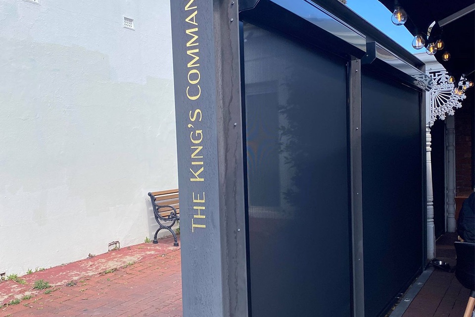 Dark mesh outdoor blinds around a pub's outdoor dining area