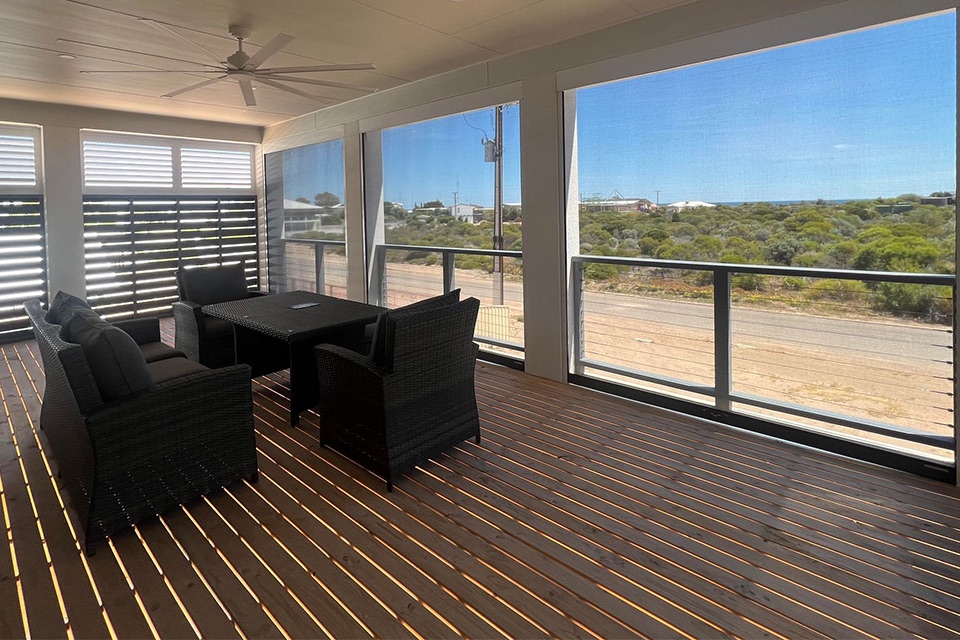 Deck under a patio with outdoor blinds, louvred screens and outdoor lounge furniture