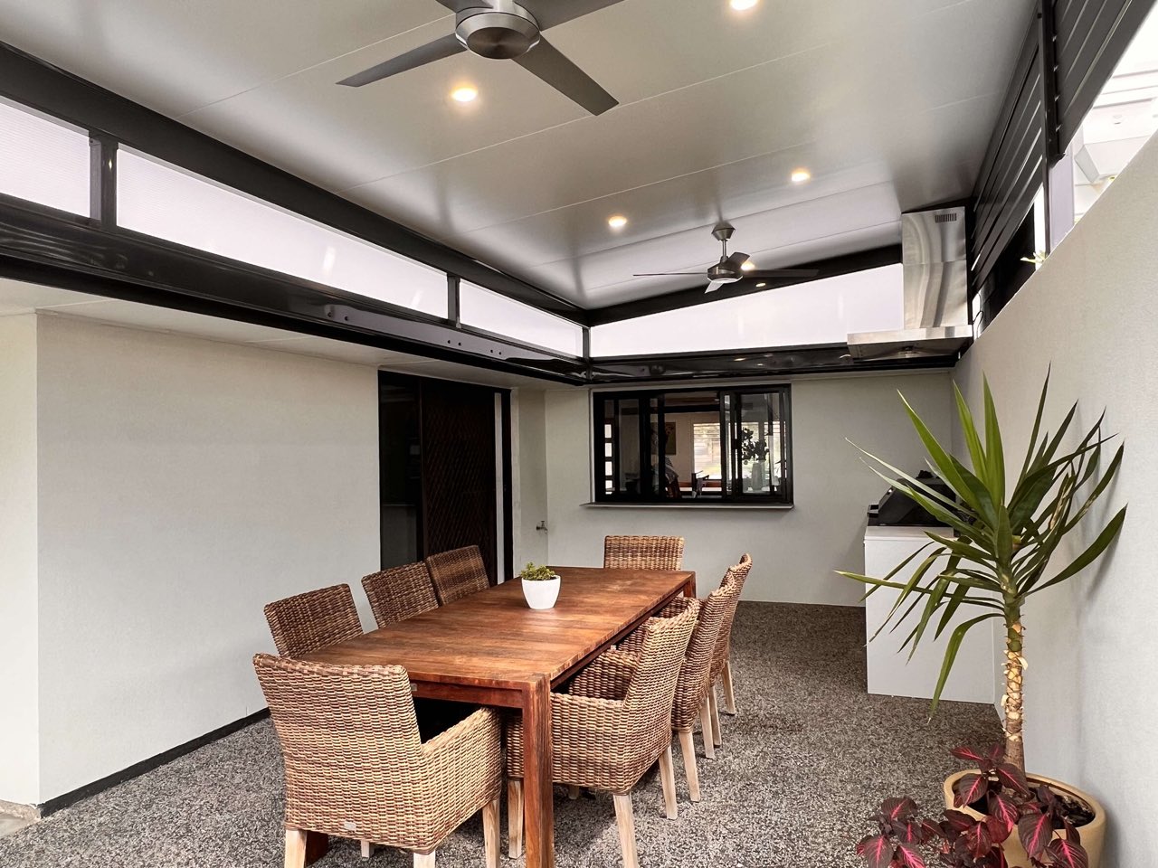 Flyover patio lifted above the house with a translucent strip, an insulated ceiling, downlights and two ceiling fans over outdoor dining