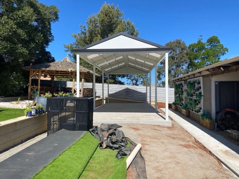 Freestanding gable patio on its own posts over a new concrete slab in a landscaped backyard