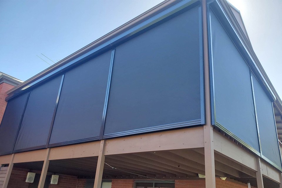Charcoal outdoor blinds enclosing a raised deck under a gable roof