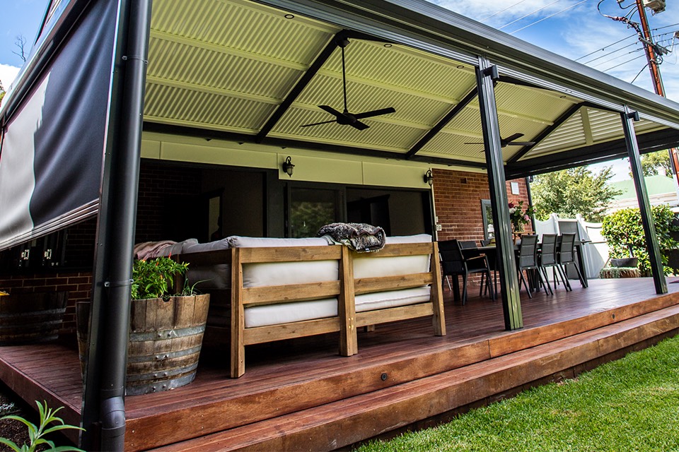 Raised timber deck under a verandah with a ceiling fan, outdoor lounge and dining