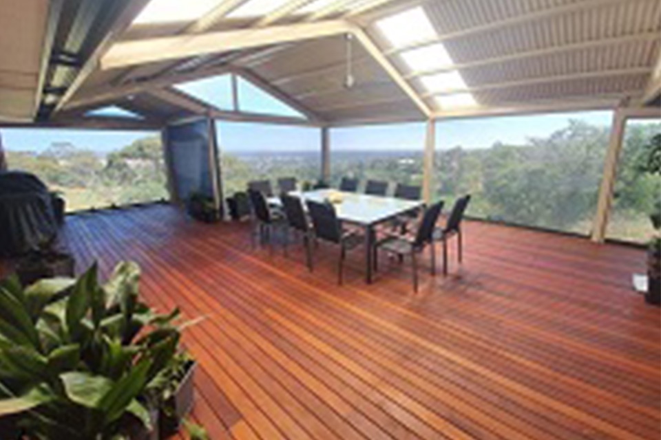 Timber deck under a gable roof with outdoor dining and a view over the hills