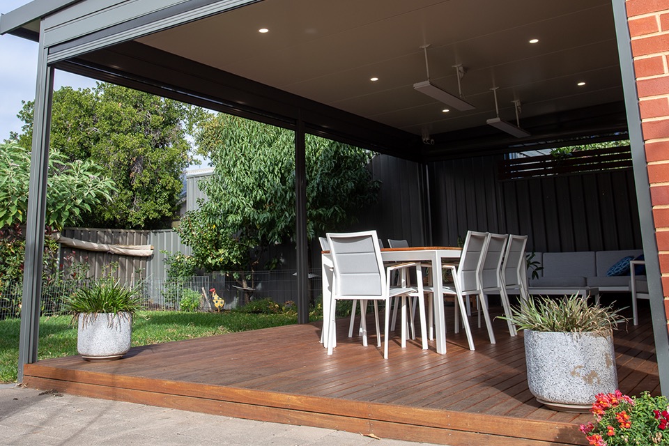Timber deck under a patio with a dark ceiling, downlights and outdoor dining