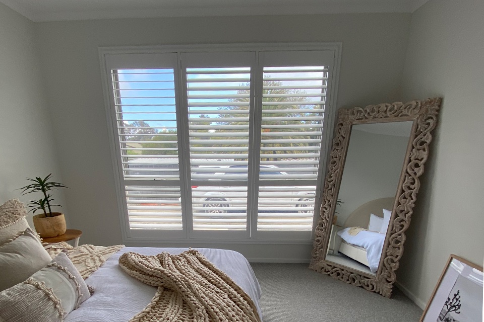 White plantation shutters on a three-panel bedroom window